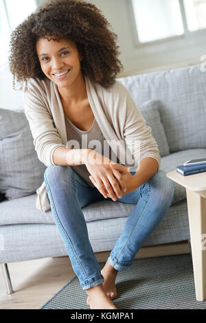 Beuatiful mixed race woman relaxing in canapé Banque D'Images