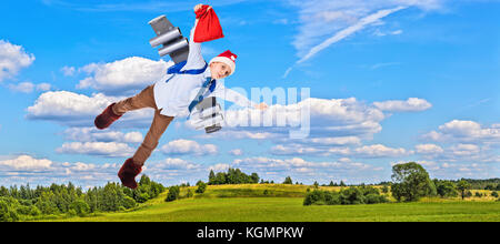 Jeune père noël volant dans le ciel avec des présents pour Noël sur un jet pack Banque D'Images