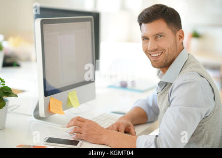 Handsome businessman working on desktop computer in office Banque D'Images