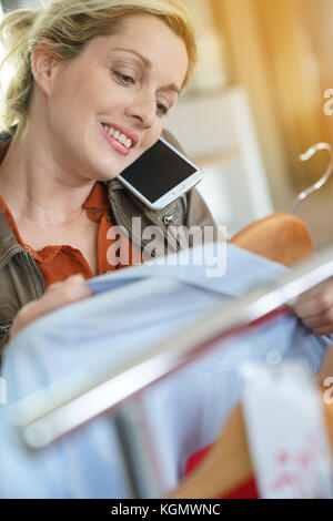 Femme parlant au téléphone avec son ami tout en faisant des emplettes dans une boutique de vêtements Banque D'Images