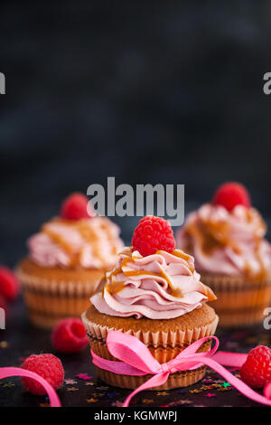 De délicieux petits gâteaux au caramel et framboise sur fond sombre Banque D'Images