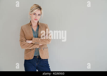 Middle-aged woman standing sur fond gris, isolé Banque D'Images