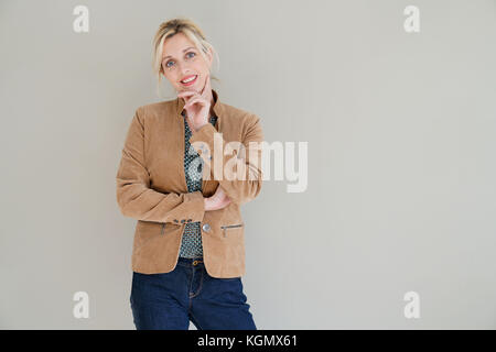 Middle-aged woman standing sur fond gris, isolé Banque D'Images