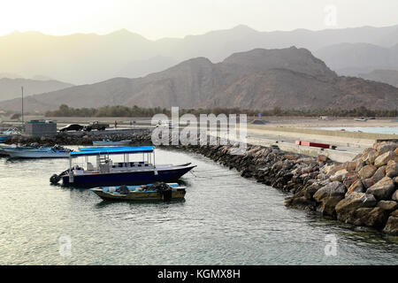 Vue sur un petit port d'Oman pendant le coucher du soleil, les montagnes Al Hajar en arrière-plan Banque D'Images