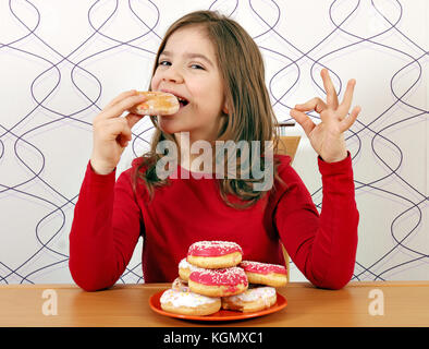 Petite fille faim manger des beignets sucrés Banque D'Images