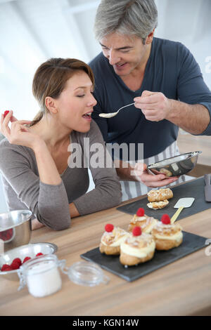 L'homme ayant sa femme préparation gâteau dégustation Banque D'Images