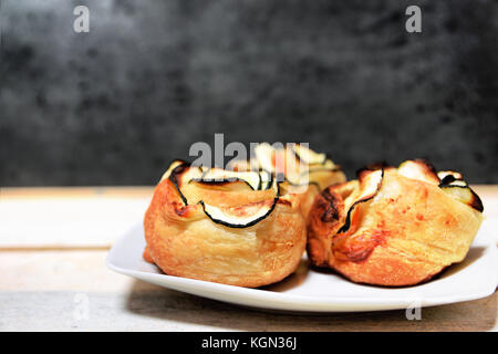 Repas typiquement espagnol avec quelques légumes et saumon fumé roulé. fleurs formant table en bois blanc sur fond noir. Banque D'Images