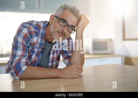 Homme d'âge moyen avec des cheveux gris en cuisine Banque D'Images