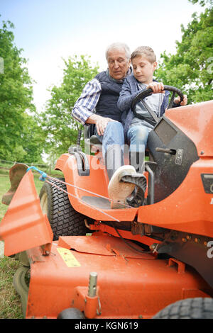 Man grandkid équitation sur tondeuse Banque D'Images