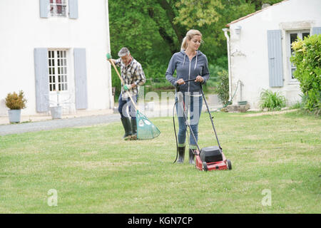 Woman in garden tondre la pelouse Banque D'Images