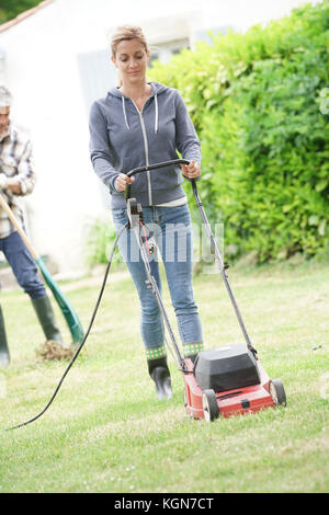 Woman in garden tondre la pelouse Banque D'Images