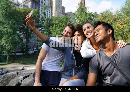 Amis en tenue de sport en utilisant smartphone à central park Banque D'Images