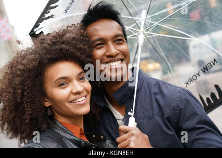 Ethnic couple walking in new york city street sur jour de pluie Banque D'Images