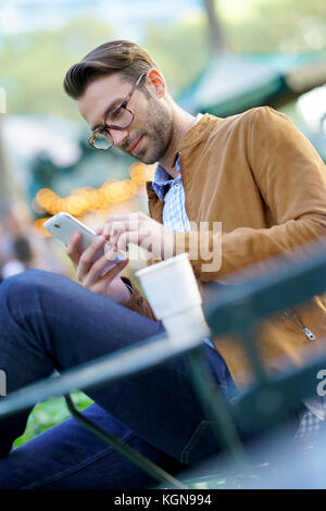 Businessman talking on phone sitting in park Banque D'Images