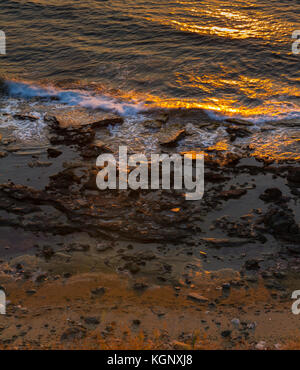 Vagues sur un éperon seashore et réflexions du soleil au coucher du soleil. Tourné en pomos, région de Paphos, Chypre Banque D'Images