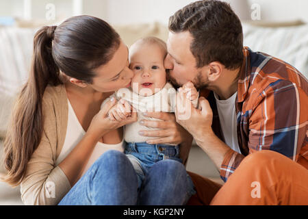 Heureux père et mère embrassant bébé à la maison Banque D'Images