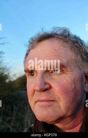 Close up visage de 60 ans à la recherche de l'homme blanc en soleil du soir au wildfowl sur un lac Banque D'Images