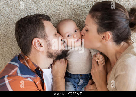 Happy Family lying on floor et d'embrasser leur bébé Banque D'Images