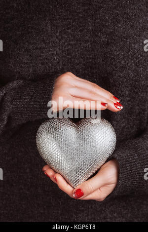 Woman's hands avec belle manucure précis garder soigneusement silver heart Banque D'Images