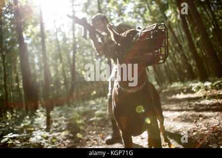 Photo de joueur d'airsoft avec mitraillette et chien Banque D'Images