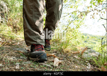 Des chaussures de randonnée avec lacets rouges et les jambes de pantalon brun porter un randonneur marchant sur un chemin dans le bois Banque D'Images
