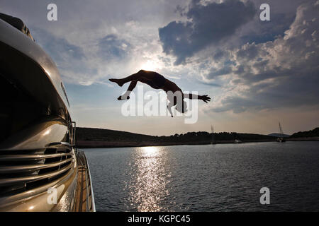 Man Jumping off yacht de luxe dans un magnifique cadre de l'océan, Hvar, Croatie Banque D'Images