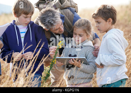 En enseignant les enfants à la campagne pour découvrir les plantes et les fleurs Banque D'Images