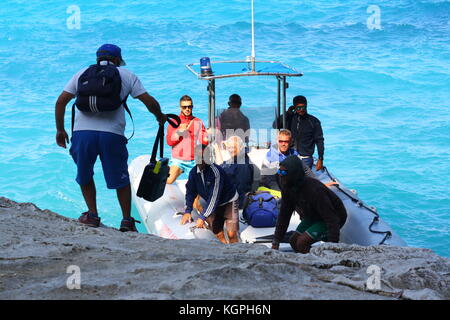 Un homme monte à bord d'un petit bateau gonflable Vigilanza sur l'eau de mer bleue dans un parc national sarde. Banque D'Images