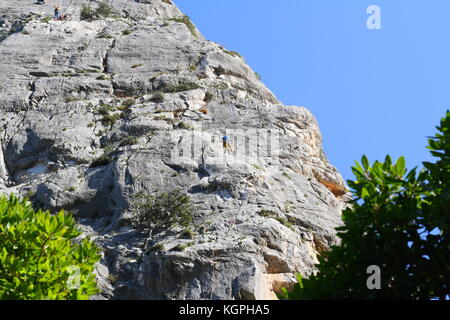 Les alpinistes qui montent vers le haut sommet d'un rocher, vu de dessous. Banque D'Images