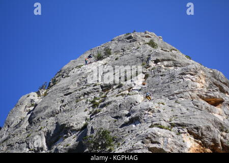 Les alpinistes qui montent vers le haut sommet d'un rocher, vu de dessous. Banque D'Images