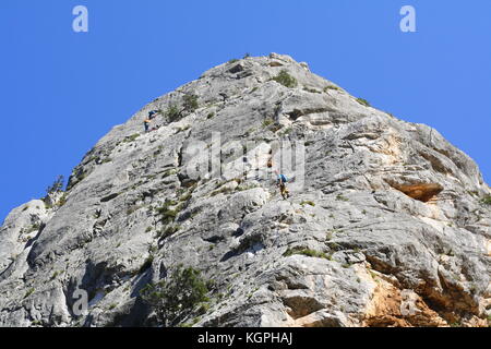 Les alpinistes qui montent vers le haut sommet d'un rocher, vu de dessous. Banque D'Images