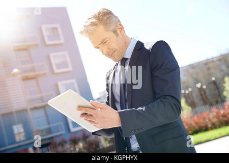 Businessman working on laptop in front of office building Banque D'Images