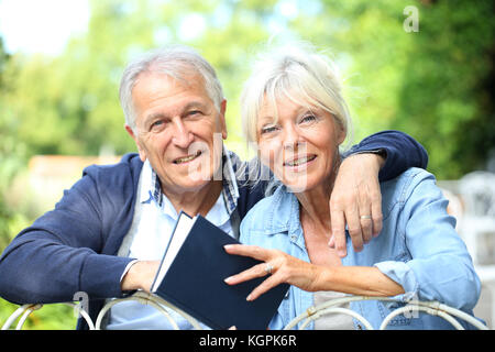 Senior couple relaxing in garden et reading book Banque D'Images