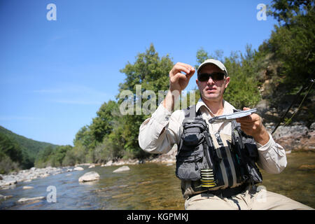 Flyfisherman choisissant une mouche artificielle pour canne à pêche Banque D'Images