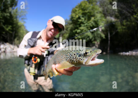 Fly fisherman holding truite fario a rencontré récemment Banque D'Images