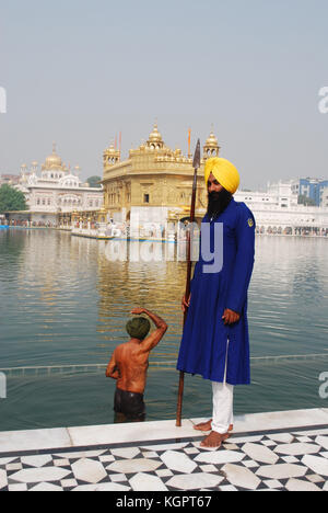 Un garde Sikh avec un homme derrière le sacré dans le bain l'Amrit Sarovar Lake, en face du Golden Temple, Amritsar, Punjab, India Banque D'Images