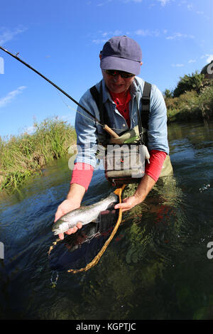 Fly fisherman holding poissons récemment pêchés Banque D'Images