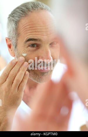 Man in front of mirror appliquer des cosmétiques Banque D'Images