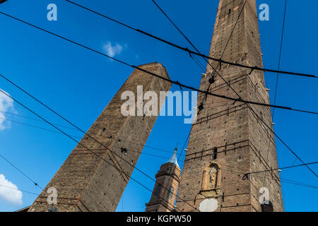 Fils de tramway criss cross le ciel bleu à la recherche à l'Asinelli et Garisenda tours médiévales, la ville de Bologne, Italie la vie. Banque D'Images