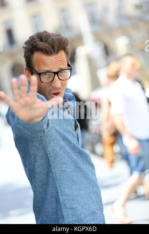 Cheerful guy avec lunettes pointing at camera Banque D'Images