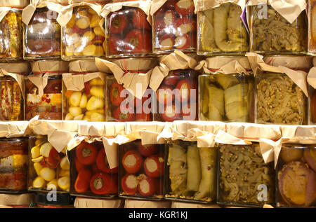 Pots de produits typiques italiens sous l'huile avec les courgettes, les poivrons, l'ail et les autres légumes frais dans l'huile culinaire de la Méditerranée tr Banque D'Images