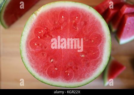 Un petit, Doux, bébé sans pépins de pastèque, est réduit de moitié sur une planche à découper de cuisine, révélant ses fruits rose frais. Banque D'Images