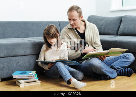 Père et fille sont la lecture de livres. le chiot est liying sur les jambes. Banque D'Images