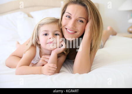 Portrait of cute little girl avec maman portant sur le lit Banque D'Images