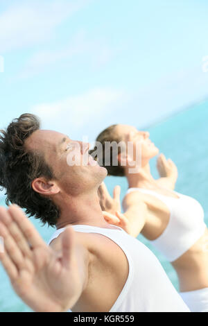 Couple doing yoga et exercices de relaxation par la mer Banque D'Images