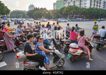 Guilin, Chine - 14 septembre 2017 : Scooters chauffeurs attendent pour feu vert sur une intersection au centre-ville de Guilin au lever du soleil. Banque D'Images