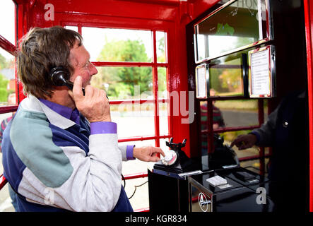 Homme résident local à l'aide d'un téléphone rouge traditionnel fort qui a été convertie en un petit centre de visiteurs. l'intérieur de la boîte de téléphone a maintenant une Banque D'Images