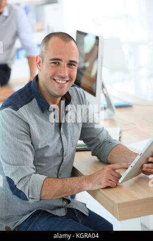 Jeune homme souriant en classe formation using digital tablet Banque D'Images