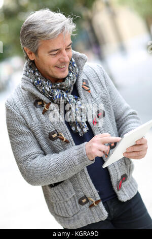 L'homme en ville rue using digital tablet Banque D'Images