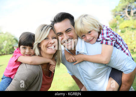 Les parents qui piggyback ride to kids in park Banque D'Images